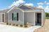 Charming modern home with gray siding and black accents, nestled in a landscaped environment with a bright blue sky backdrop.