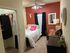 Cozy bedroom with vibrant red accent wall, stylish decor, and natural light from a window. Features a comfortable bed, modern desk, and chic wall art, perfect for a relaxing retreat.
