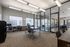 Modern office space with sleek desks, comfortable chairs, large windows, and bright overhead lighting, perfect for productivity.