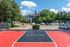 Inviting basketball court at an apartment complex, surrounded by vibrant greenery and ample parking, showcasing a perfect blend of recreation and convenience.