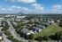 Scenic aerial view of modern apartment complex with lush greenery, spacious layouts, and stunning city skyline in the distance.