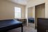 Cozy bedroom with plush carpet, large mirrored closet, and ample natural light through a wide window, ideal for relaxation.