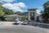 Charming apartment complex entrance with modern architecture, lush greenery, and convenient parking.