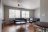 Bright and inviting apartment lounge with modern black seating, hardwood floors, and large windows flooding the space with natural light.