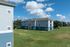 Charming apartment complex with modern blue exterior and vibrant green lawn under a clear, blue sky with fluffy clouds.