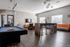 Chic modern lounge area with a stylish pool table, cozy seating, wall-mounted TV, and a sleek breakfast bar under decorative lighting.