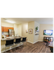 Modern apartment with open kitchen featuring a sleek countertop and bar stools, complemented by stylish wooden flooring and a cozy living space with wall-mounted TV.