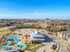 Vibrant aerial view of a modern residential complex featuring a unique resort-style pool, surrounded by lush greenery and scenic landscapes.