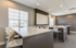 Modern conference room with sleek white tables and chairs, complemented by natural light and a ceiling-mounted projector screen.