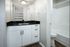 Sleek and modern bathroom featuring elegant black marble countertop, stylish white cabinetry, and inviting lighting.