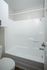 Modern bathroom with sleek white tub and shower, elegant fixtures, and stylish cabinetry.