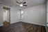 Spacious bedroom with elegant wood flooring, neutral walls, and a ceiling fan, leading to a bright, modern en-suite bathroom.