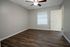 Modern bedroom boasting elegant wood flooring, a ceiling fan for comfort, and a window with natural light filtering through blinds.