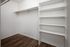Spacious modern closet with built-in shelving and sleek wooden flooring, perfect for organized storage solutions.
