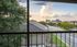 Stunning apartment view showcasing a lively neighborhood, lush trees, and a distant stadium under a vibrant sky.