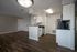 Modern apartment interior featuring a sleek kitchen with granite countertops and spacious open-plan living area with elegant wood flooring.