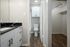 Elegant bathroom with sleek black marble countertop, spacious walk-in closet, and modern cabinetry, complemented by warm wood flooring.