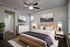 Elegant bedroom with a modern design, featuring a cozy bed, stylish decor, and large artwork, illuminated by natural light.
