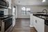 Modern kitchen with sleek stainless steel appliances, elegant dark countertops, and wood flooring, offering a chic and stylish open space.