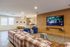 Inviting open-concept room with a cozy plaid couch, stylish wooden accents, and modern kitchen bar area, perfect for relaxation and entertaining.