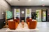 Welcoming seating area featuring plush orange chairs, a small table, and decorative wall art.