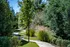 Charming park pathway lined with lush greenery and elegant lampposts, perfect for serene walks and outdoor relaxation.