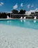 Inviting outdoor pool with a volleyball net, perfect for fun and relaxation under a bright blue sky.