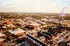 Aerial view of a vibrant urban neighborhood featuring modern red brick buildings, lush greenery, and a purple arrow highlighting a significant site. Perfect blend of serene residential area and bustling city life.