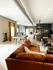 Modern loft-style apartment with a luxurious brown leather sofa, stylish pool table, and industrial chic decor.