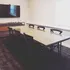 Modern conference room with glass-top table, sleek black chairs, and a large wall-mounted TV for presentations.