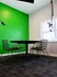 Modern room with a vibrant green accent wall, round table, and stylish chairs, perfect for creative meetings.