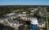 Aerial view of a modern apartment complex surrounded by lush greenery, spacious parking, and a prominent Big Rapids water tower emphasizing the community's welcoming vibe.