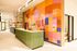 Vibrant modern lobby with colorful geometric mural and sleek green reception desk, creating an inviting and artistic atmosphere.