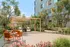 Charming outdoor patio featuring modern orange seating, lush greenery, and a sleek barbecue area under a stylish wooden pergola.