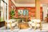 Elegant living area featuring modern decor, lush green plants, cozy seating, and vibrant artwork on rustic wooden panels.