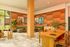 Inviting apartment lounge with vibrant artwork, lush greenery, cozy seating, and a stylish wooden dining table.
