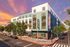 Vibrant modern apartment building with colorful mural, street view featuring trees and parked cars under a stunning sunset sky.