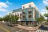 Modern multi-story apartment building with vibrant exterior mural, featuring a trendy corner cafe and lush street landscaping.