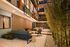 Modern apartment courtyard with chic outdoor seating, lush green bamboo, and elegant lighting creating a tranquil ambiance.