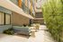 Chic apartment patio with modern seating, lush bamboo plants, and elegant outdoor dining area, offering a tranquil oasis.