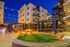 Elegant apartment courtyard illuminated with charming string lights, featuring cozy seating areas and lush greenery, ideal for evening relaxation.