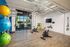 Bright and modern fitness room featuring exercise bikes, vibrant stability balls, and a large ceiling fan for enhanced comfort.