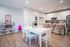 Charming open-concept dining and kitchen area with elegant white cabinetry, inviting breakfast bar with plush stools, and cozy dining table set against stylish wood flooring.