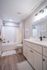Elegant, modern bathroom with sleek white cabinetry, stylish lighting, and a spacious shower-tub combo.