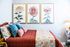 Charming bedroom with vibrant floral art, cozy red quilted bedding, and decorative cushions creating a warm, inviting atmosphere.