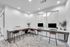 Modern communal office space with sleek computers, stylish high stools, and lush greenery, perfect for productivity and collaboration.