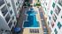 Modern apartment courtyard with a stylish pool surrounded by sun loungers and greenery, perfect for relaxation and leisure.