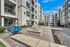 Modern apartment courtyard with elegant stone benches, a stylish hanging chair, and lush greenery, offering a welcoming communal space.