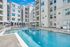 Luxurious apartment complex with a pristine swimming pool, sun loungers, and modern architecture ideal for relaxation and leisure.