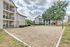 Inviting apartment complex with charming balconies overlooking a well-maintained sand volleyball court and lush greenery.